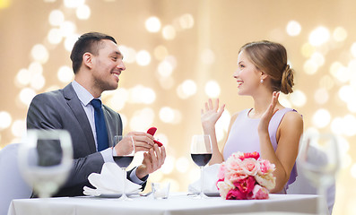 Image showing man giving woman engagement ring at restaurant