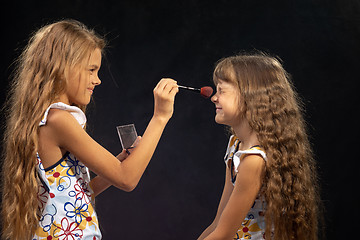 Image showing Girl powdering nose to her sister, sister squinting from tickling