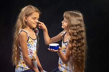 Image showing Girl puts cream on her sister\'s nose