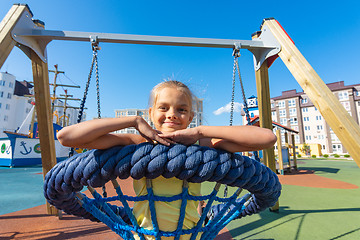 Image showing Girl riding a round hanging swing in the playground