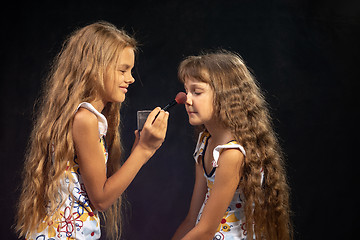 Image showing Older sister powders nose to younger sister