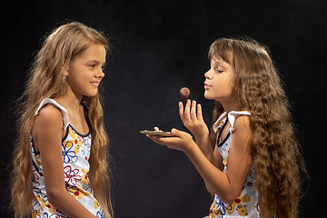 Image showing A girl blows on a brush with powder, another girl looks closely at her closely