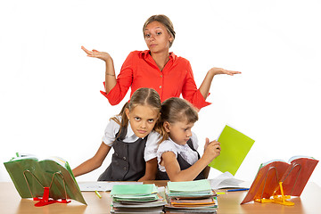 Image showing Two girls are pushing while sitting at a desk, the teacher does not know what to do with it