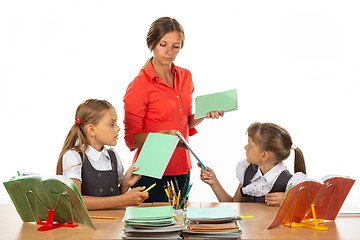 Image showing Upset children hand over notebooks to teacher