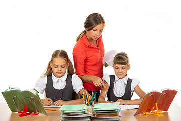 Image showing The teacher helps schoolgirls in the lesson, prompting how to solve the problem