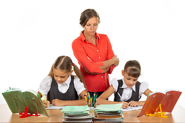 Image showing A strict teacher stands above the children who solve the task