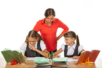 Image showing Teacher and student look in the notebook of another student, where something funny