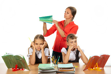 Image showing The teacher considers the number of notebooks handed over, the girls in the foreground frankly miss