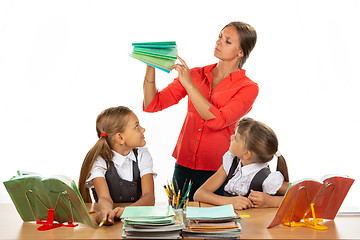 Image showing The teacher considers the notebooks of students, two schoolgirls look at her with interest