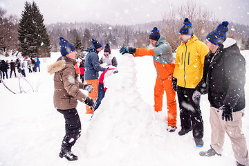 Image showing group of young people making a snowman