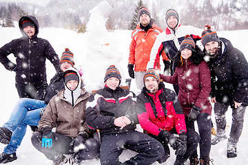 Image showing group portait of young people posing with snowman