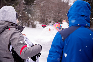 Image showing group of young people making a snowman