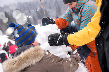 Image showing group of young people making a snowman