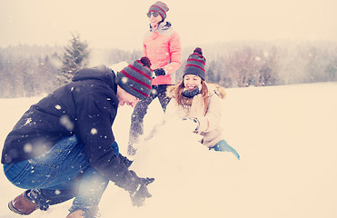 Image showing group of young people making a snowman