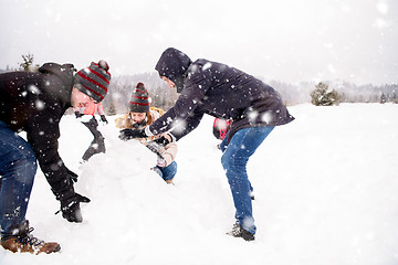 Image showing group of young people making a snowman