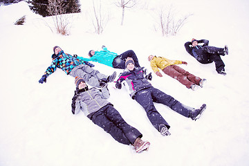 Image showing group of young people laying on snow and making snow angel