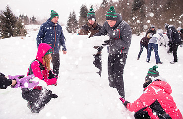 Image showing group of young people making a snowman