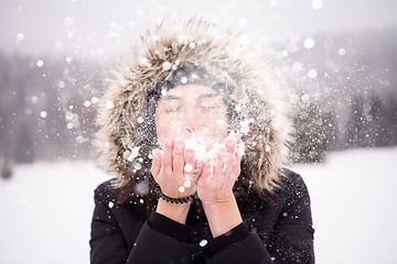 Image showing young woman blowing snow on snowy day
