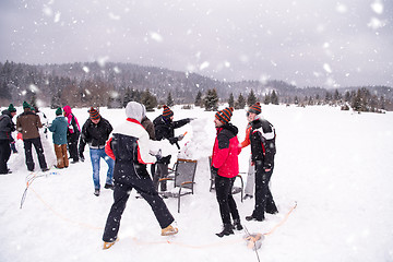 Image showing group of young people making a snowman