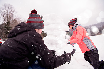 Image showing group of young people making a snowman