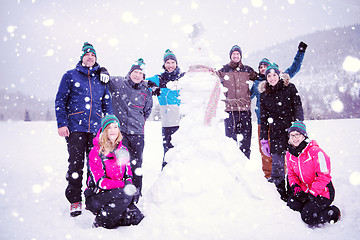 Image showing group portait of young people posing with snowman