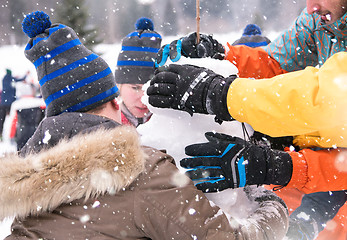 Image showing group of young people making a snowman