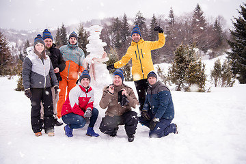 Image showing group portait of young people posing with snowman