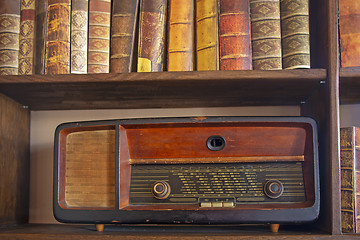 Image showing Old vintage radio on the wooden shelf with books