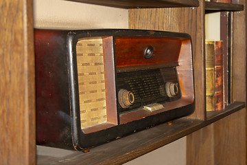 Image showing Old vintage radio on the wooden shelf with books