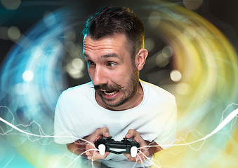 Image showing Enthusiastic gamer. Joyful young man holding a video game controller