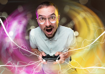 Image showing Enthusiastic gamer. Joyful young man holding a video game controller