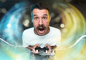 Image showing Enthusiastic gamer. Joyful young man holding a video game controller