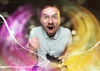 Image showing Enthusiastic gamer. Joyful young man holding a video game controller