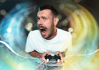 Image showing Enthusiastic gamer. Joyful young man holding a video game controller