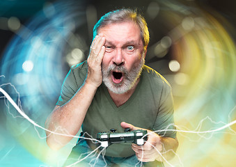 Image showing Enthusiastic gamer. Joyful man holding a video game controller