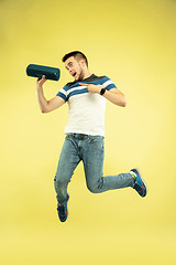 Image showing Full length portrait of happy jumping man with gadgets on yellow background