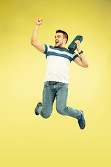 Image showing Full length portrait of happy jumping man with gadgets on yellow background