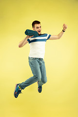 Image showing Full length portrait of happy jumping man with gadgets on yellow background