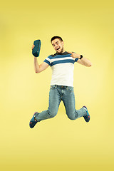 Image showing Full length portrait of happy jumping man with gadgets on yellow background