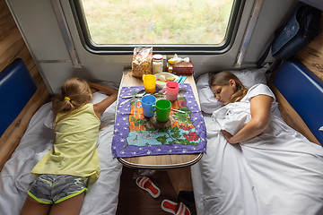 Image showing The situation on the train, mom and daughters are sleeping on the lower shelves in the car