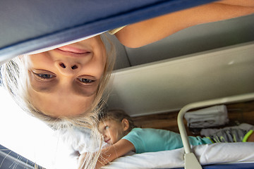 Image showing A girl hanging from the top shelf in a train looks into the frame