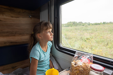 Image showing Girl sitting in a reserved seat wagon looks tiredly out the window