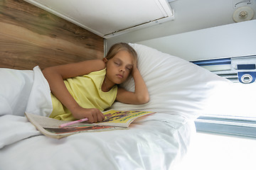 Image showing Girl fell asleep reading a magazine on the top shelf of a reserved seat car