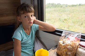 Image showing A girl sitting in a reserved seat carriage in a train thoughtfully looks into the frame