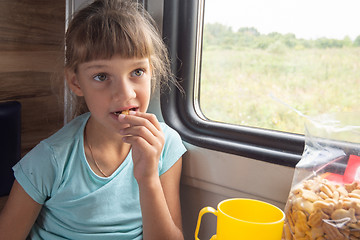 Image showing Girl eats cookies in a train