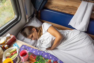 Image showing A young girl sleeps on the bottom bunk in a train