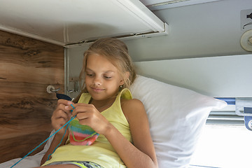 Image showing Girl knitting lying on the top shelf of the car