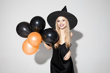 Image showing Young woman in hat as a witch on white background