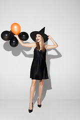 Image showing Young woman in hat as a witch on white background