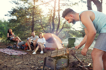 Image showing Party, camping of men and women group at forest. They relaxing, singing a song and cooking barbecue